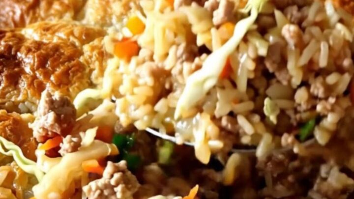 A golden, bubbling baked rice dish with ground pork and shredded cabbage in a white ceramic pan.