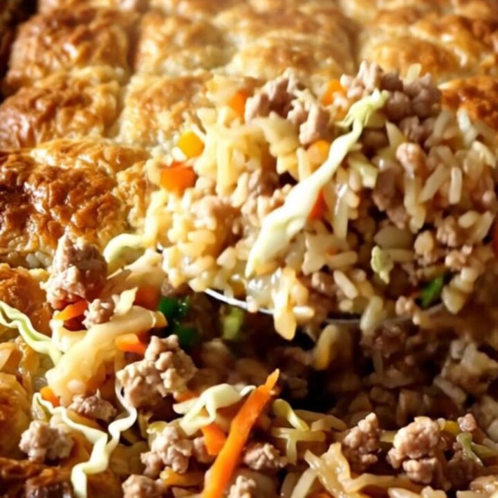 A golden, bubbling baked rice dish with ground pork and shredded cabbage in a white ceramic pan.