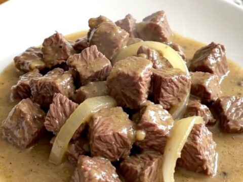 A close-up of tender beef tips in a creamy mushroom gravy served on a white plate.