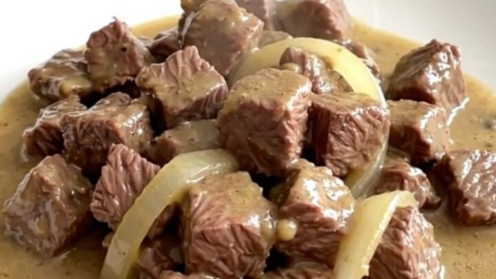 A close-up of tender beef tips in a creamy mushroom gravy served on a white plate.