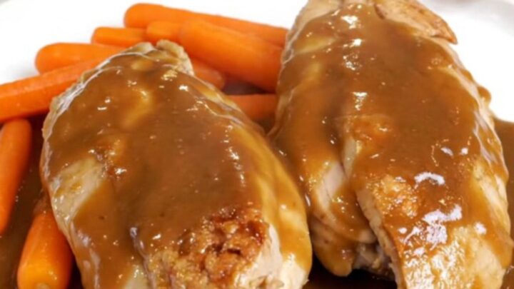 Slow cooked chicken breasts and baby carrots in a glossy brown sugar butter sauce on a white plate.