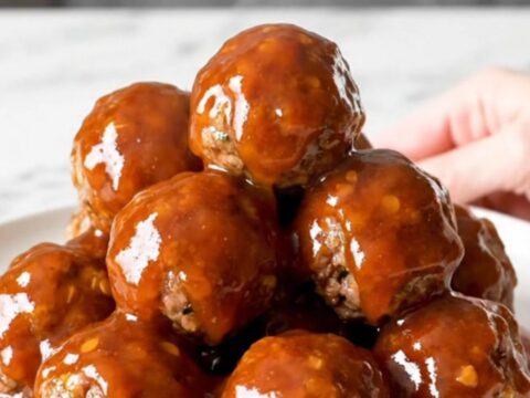 A close-up of honey chipotle meatballs in a slow cooker with a glossy red sauce.