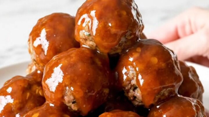 A close-up of honey chipotle meatballs in a slow cooker with a glossy red sauce.