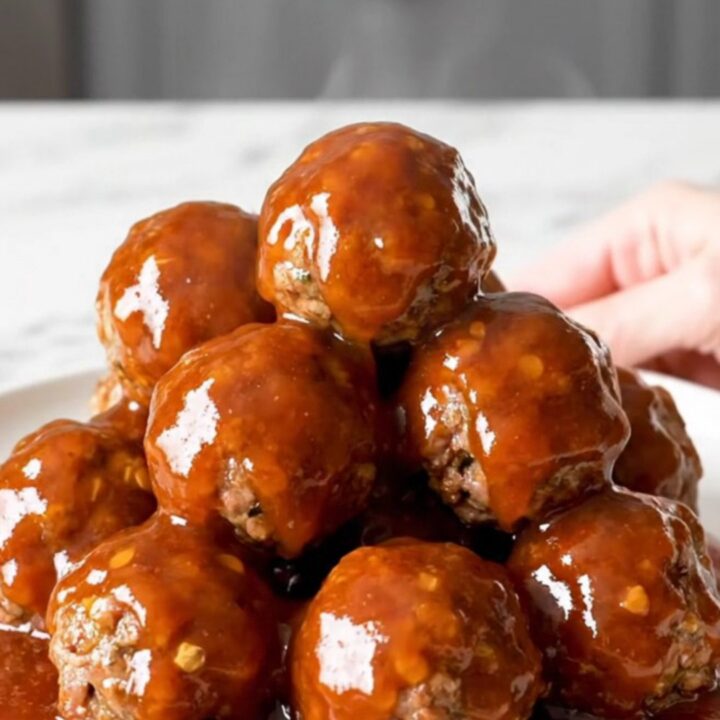 A close-up of honey chipotle meatballs in a slow cooker with a glossy red sauce.