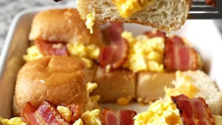 A top-down view of a rectangular baking dish filled with golden brown bacon, egg and cheese sliders.