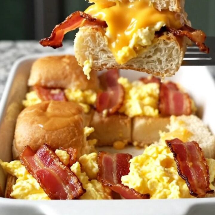 A top-down view of a rectangular baking dish filled with golden brown bacon, egg and cheese sliders.