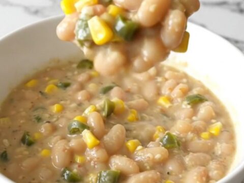 A steaming bowl of creamy white bean chili topped with corn and green chiles.