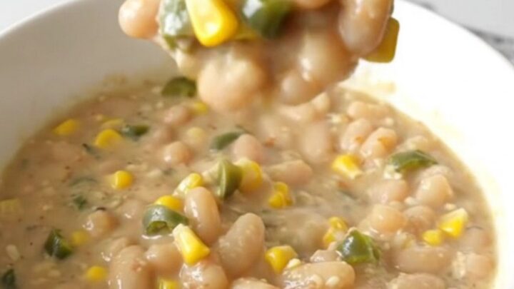 A steaming bowl of creamy white bean chili topped with corn and green chiles.