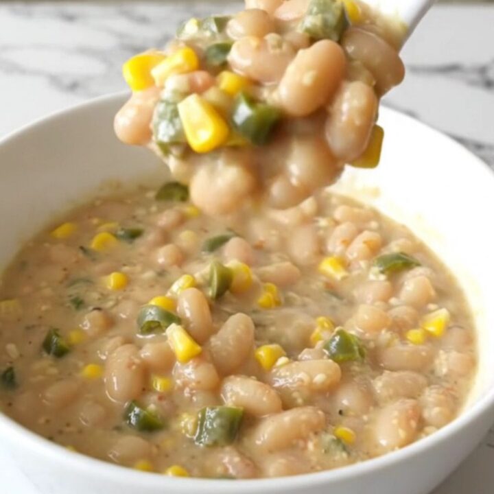 A steaming bowl of creamy white bean chili topped with corn and green chiles.