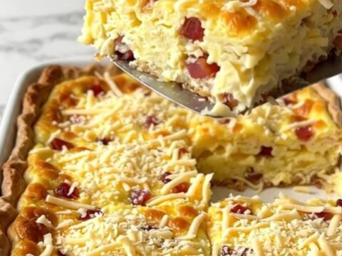 A golden, crustless Quiche Lorraine in a white ceramic baking dish on a quartz counter.