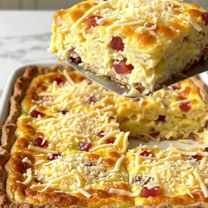 A golden, crustless Quiche Lorraine in a white ceramic baking dish on a quartz counter.