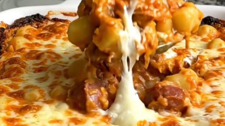 A top-down view of a rectangular baking dish filled with gnocchi, sliced smoked sausage, tomato sauce, and mozzarella.
