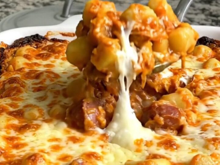 A top-down view of a rectangular baking dish filled with gnocchi, sliced smoked sausage, tomato sauce, and mozzarella.