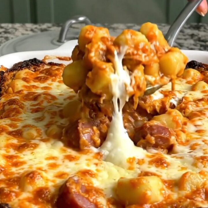 A top-down view of a rectangular baking dish filled with gnocchi, sliced smoked sausage, tomato sauce, and mozzarella.