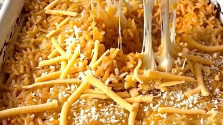 A rectangular ceramic baking dish filled with golden, cheesy Mexican rice on a granite countertop.