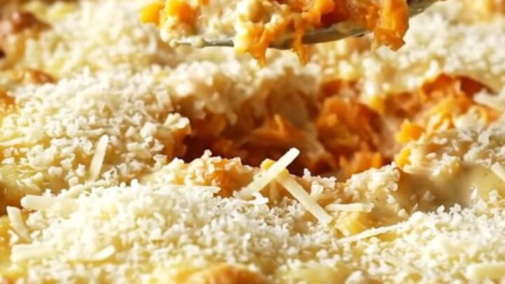 A ceramic baking dish filled with neatly layered, golden-brown parmesan scalloped sweet potatoes.