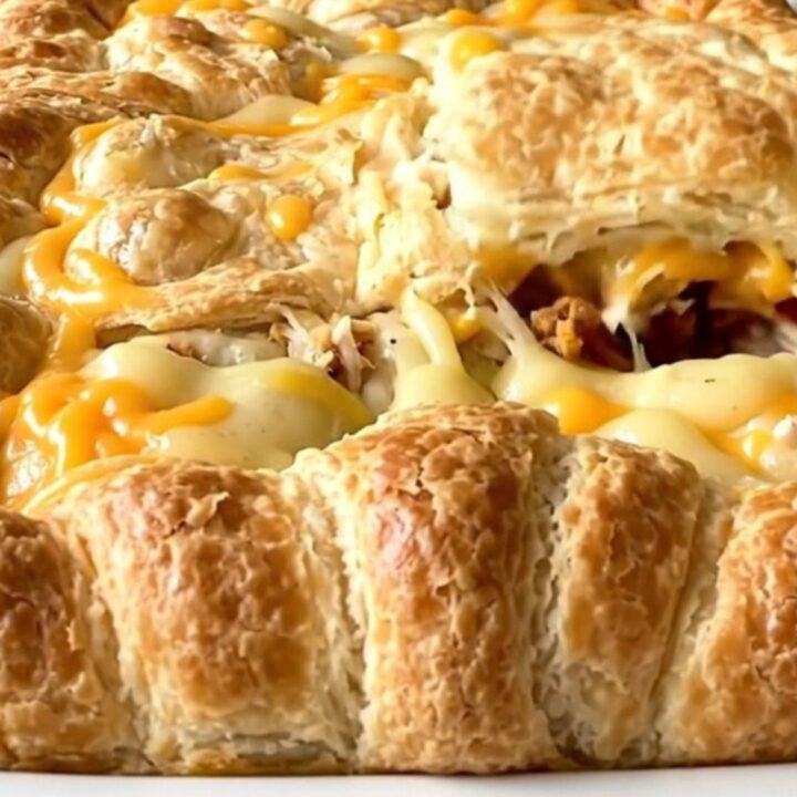 A golden-brown turkey bacon club crescent bake in a white rectangular ceramic dish on a speckled granite surface.