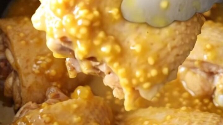 A close-up of tender, glazed chicken thighs in a slow cooker with a thick pineapple and mustard sauce.
