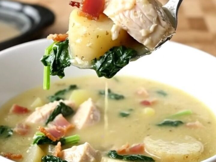 A shallow white bowl filled with creamy chicken Zuppa Toscana, showing tender chicken, potato slices, and bacon.