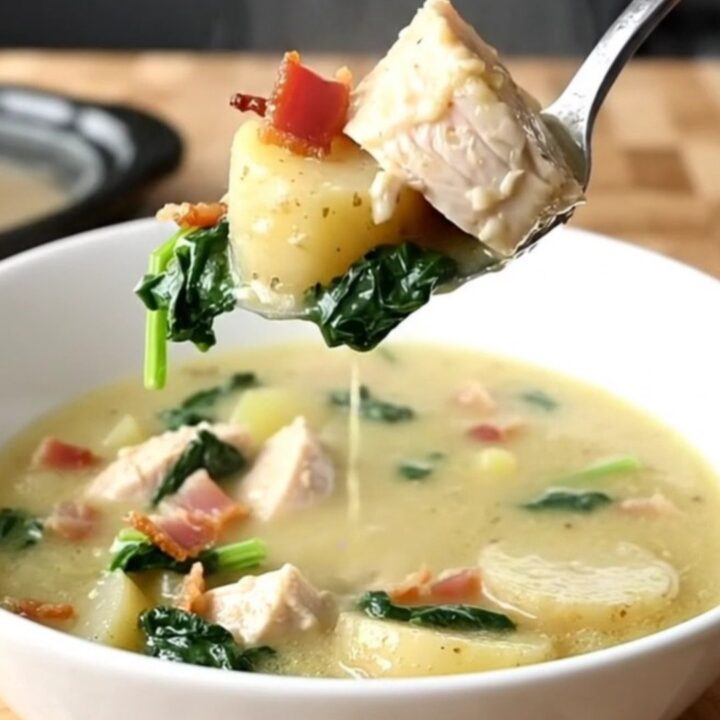 A shallow white bowl filled with creamy chicken Zuppa Toscana, showing tender chicken, potato slices, and bacon.
