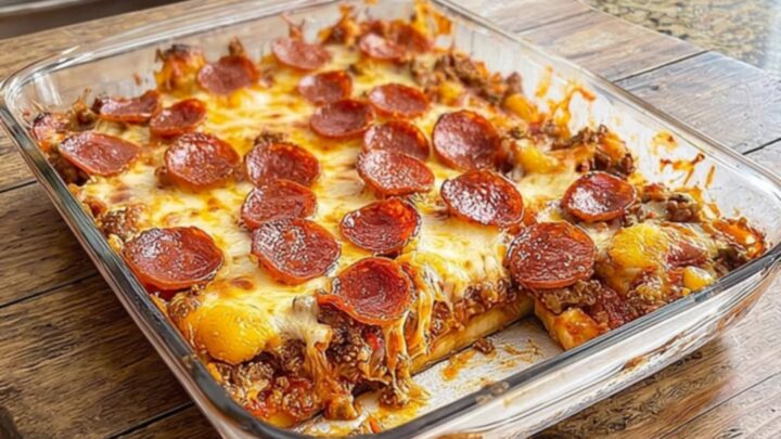 A thick, steaming slice of meat lovers pizza casserole being lifted from a glass dish with a spatula.