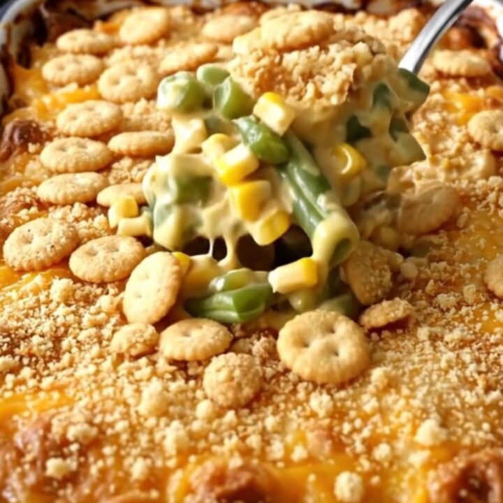 A rectangular white baking dish filled with a creamy green bean and corn casserole topped with golden cracker crumbs.