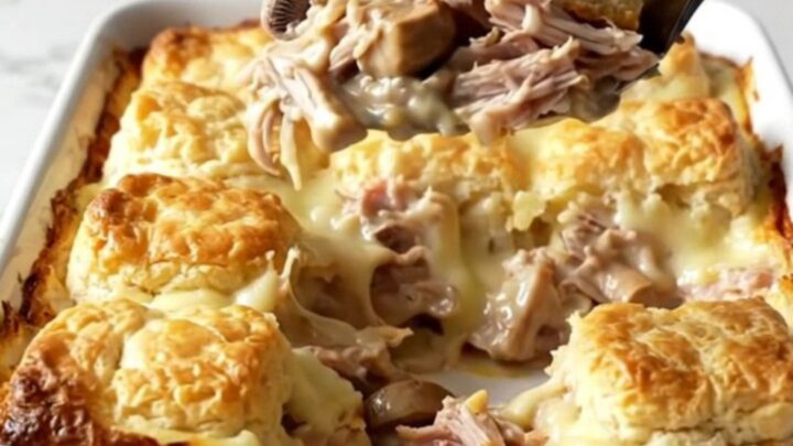 A golden, bubbly turkey and mushroom biscuit bake in a rectangular ceramic dish on a white countertop.