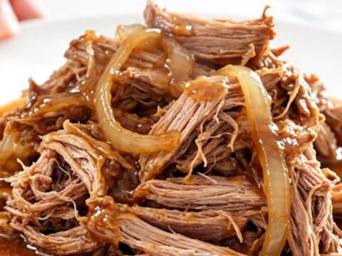 A close-up of tender, shredded pulled pork in a glossy red pepper jelly sauce.