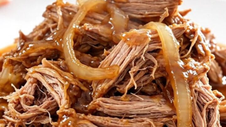 A close-up of tender, shredded pulled pork in a glossy red pepper jelly sauce.