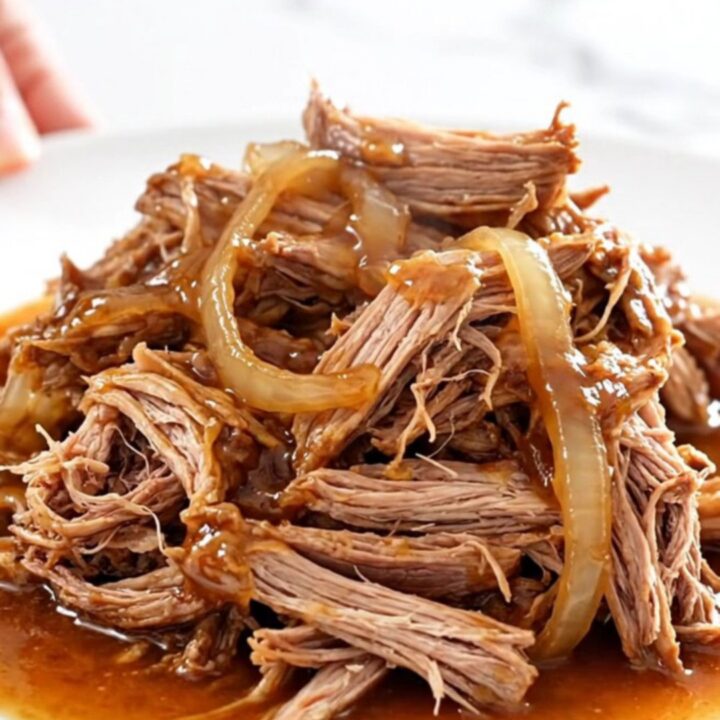 A close-up of tender, shredded pulled pork in a glossy red pepper jelly sauce.