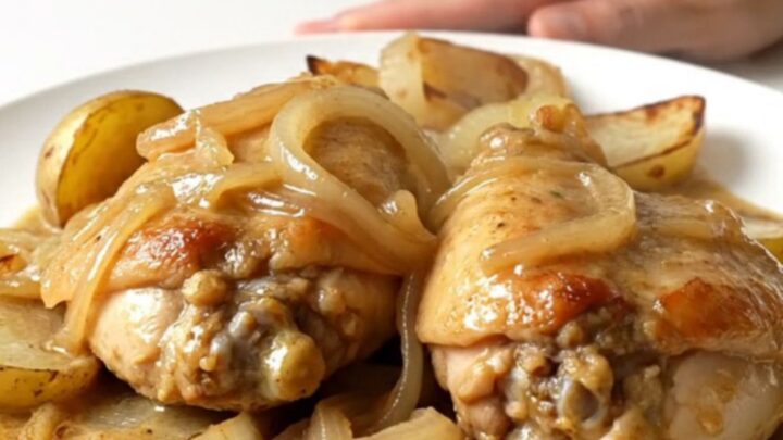 Slow cooker French onion chicken thighs with halved potatoes and a creamy onion sauce served in a white bowl.