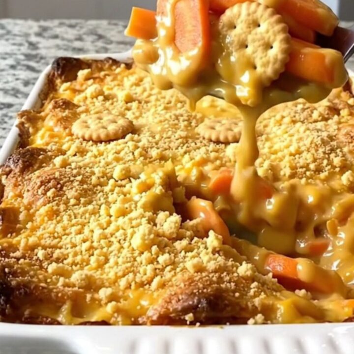 A top-down view of a golden-brown cheesy carrot casserole in a white ceramic dish.