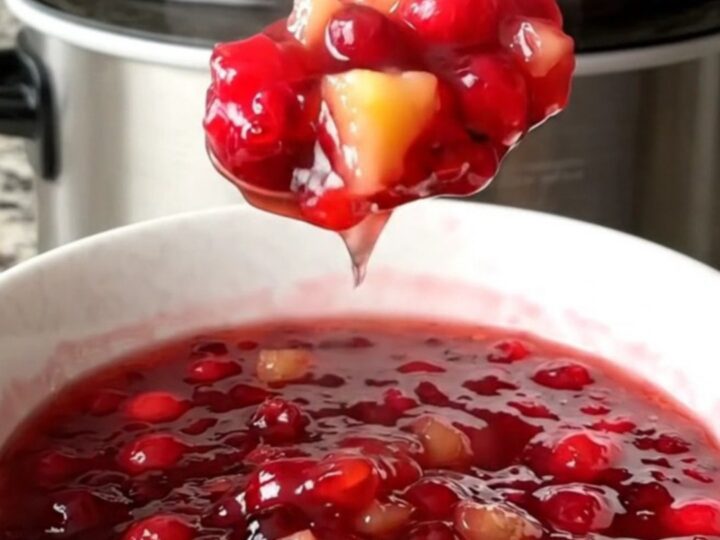 A white bowl filled with vibrant, jammy cranberry pineapple sauce made in a slow cooker.