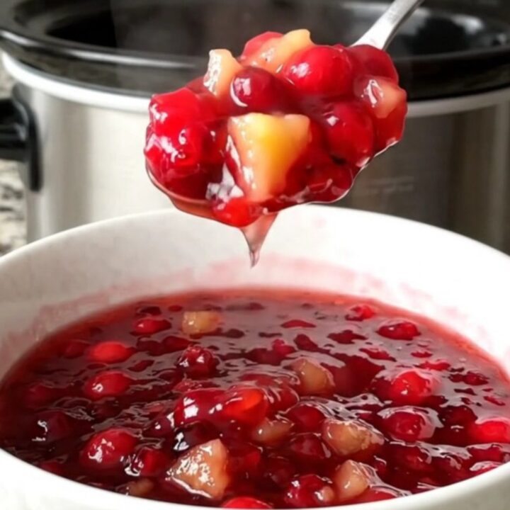 A white bowl filled with vibrant, jammy cranberry pineapple sauce made in a slow cooker.