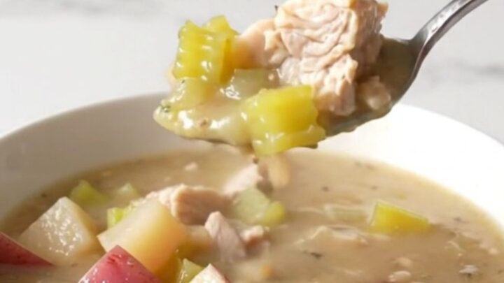 A bowl of creamy chicken and potato chowder with visible chunks of chicken, red potatoes, and celery.