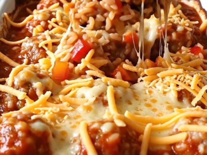 A rectangular baking dish filled with turkey meatballs, rice, and peppers, topped with melted cheese.