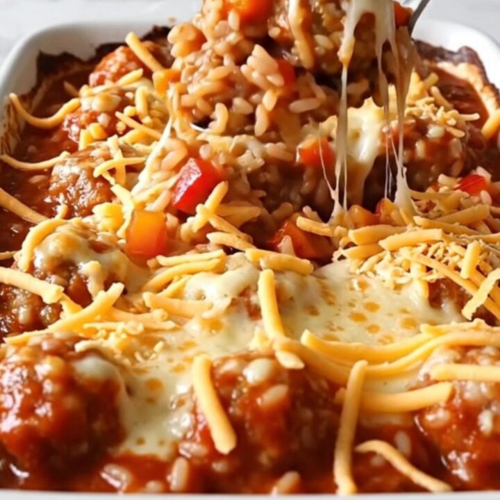 A rectangular baking dish filled with turkey meatballs, rice, and peppers, topped with melted cheese.