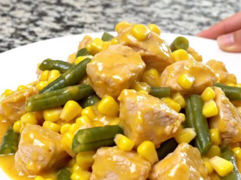A top-down view of a slow cooker filled with chicken, corn, green beans, and creamy cheddar sauce.