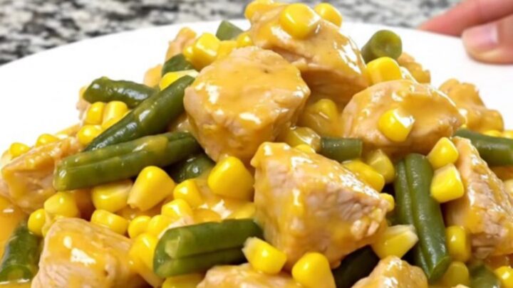 A top-down view of a slow cooker filled with chicken, corn, green beans, and creamy cheddar sauce.