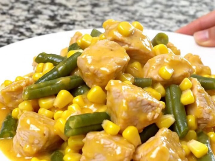 A top-down view of a slow cooker filled with chicken, corn, green beans, and creamy cheddar sauce.