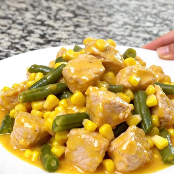 A top-down view of a slow cooker filled with chicken, corn, green beans, and creamy cheddar sauce.