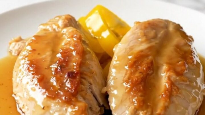 A close-up of tender, slow-cooked chicken breasts topped with bright yellow banana pepper rings and a glossy honey glaze