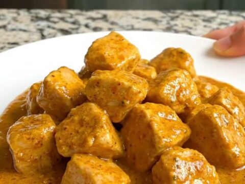 A bowl of creamy Crockpot Curry Chicken and Cauliflower served over rice.