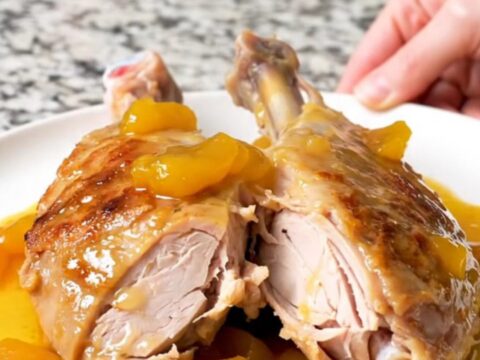 A whole, slow-cooked turkey tenderloin covered in a glossy, golden-brown apricot sauce on a white plate.