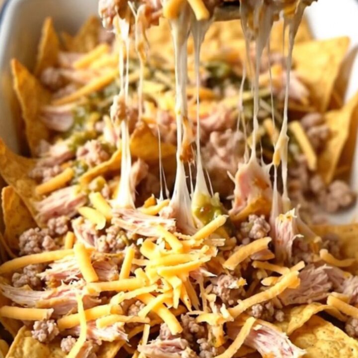 A large enameled rectangular baker filled with a layered nacho bake featuring ground turkey, salsa verde