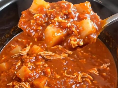 A close-up of a hearty bowl of turkey and potato chili in a rustic bowl, garnished with herbs.