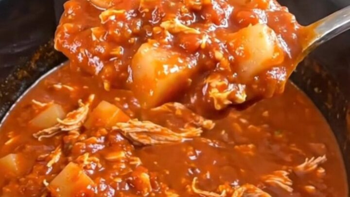 A close-up of a hearty bowl of turkey and potato chili in a rustic bowl, garnished with herbs.