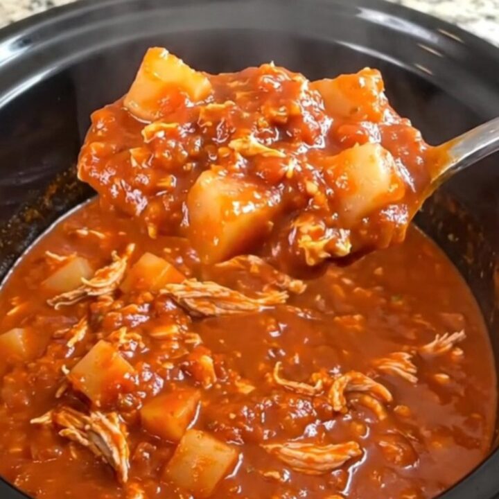 A close-up of a hearty bowl of turkey and potato chili in a rustic bowl, garnished with herbs.
