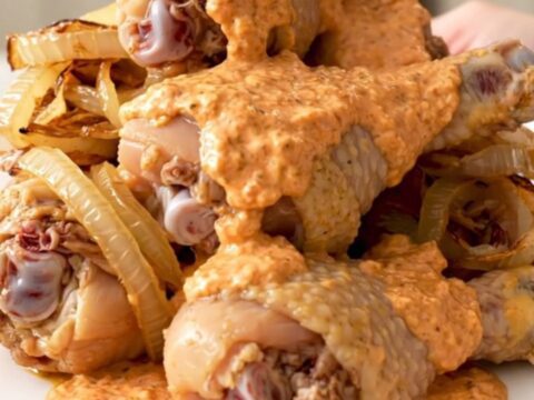 Slow cooker chicken drumsticks coated in a creamy, pink-orange comeback sauce on a white plate.
