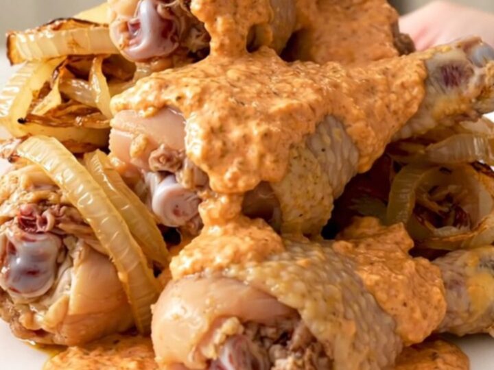 Slow cooker chicken drumsticks coated in a creamy, pink-orange comeback sauce on a white plate.